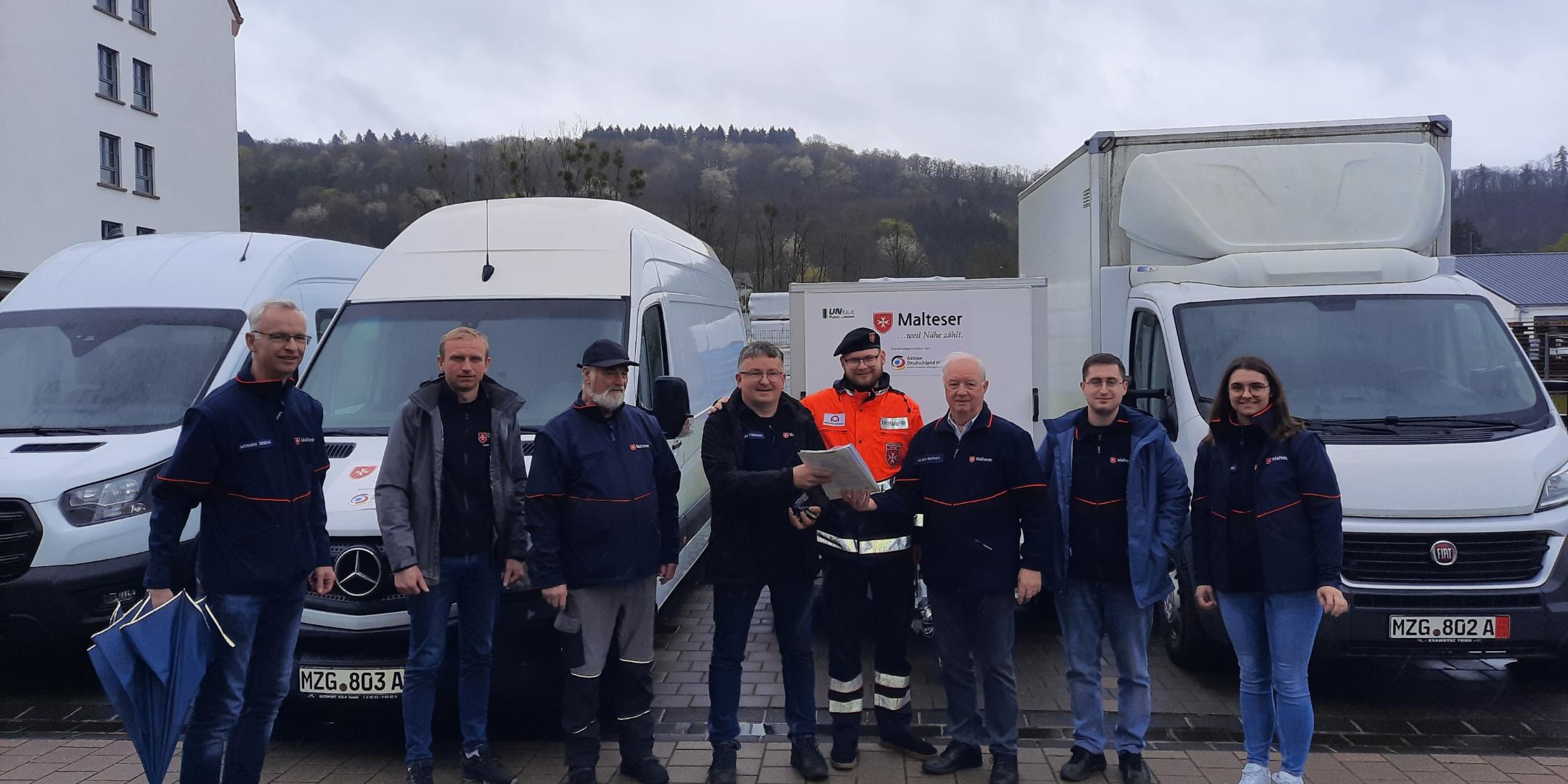 Roman Yaruchyk (Vierter von links) von den Maltesern in Ivano Frankivsk nimmt Papiere und Schlüssel der gespendeten Fahrzeuge vom Diözesanauslandsbeauftragten Ulrich Mathey (Dritter von rechts) entgegen.