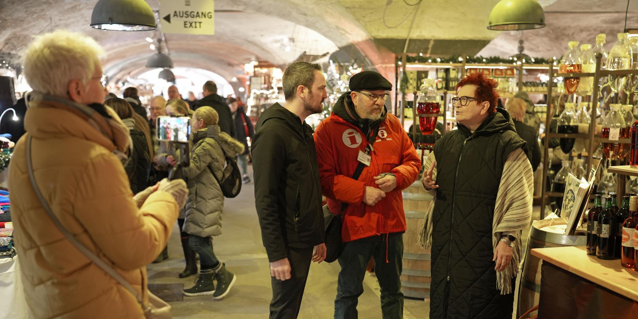 Gabriele Centurioni (rechts) und Tobias Schmitt treffen sich auf dem Wein-Nachts-Markt mit Gästeführer Günter Hauenstein (Zweiter von rechts). Monika Hochscheid (links) zeichnet das Video auf. (c) Stefan Endres Gabriele Centurioni (rechts) und Tobias Schmitt treffen sich auf dem Wein-Nachts-Markt mit Gästeführer Günter Hauenstein (Zweiter von rechts). Monika Hochscheid (links) zeichnet das Video auf.