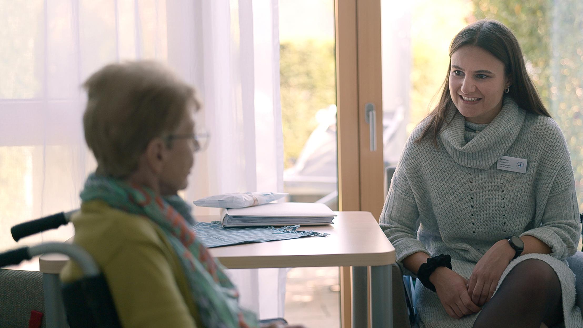 Die „Zeitschenkerin“ und Psychologiestudentin Katharina bei ihrer ehrenamtlichen Arbeit im Hospiz Bethesda in Landau. Sie spricht mit einer Bewohnerin.