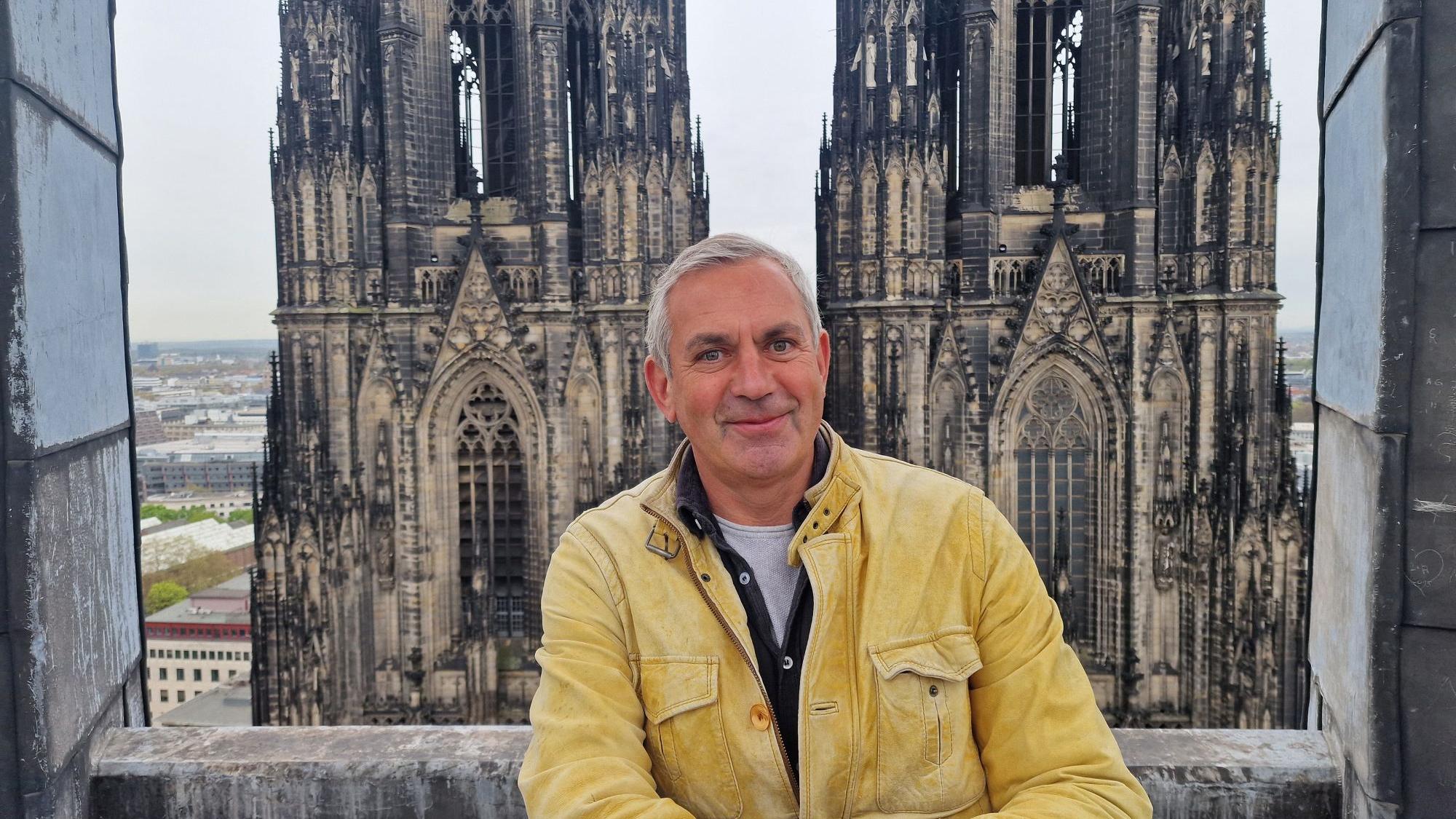 Ein Mann in gelber Jacke steht vor einer Kirche