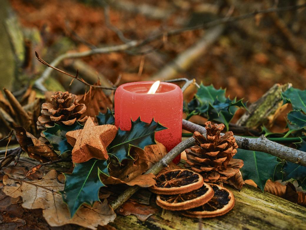 Adventsgesteck mit brennender Kerze.