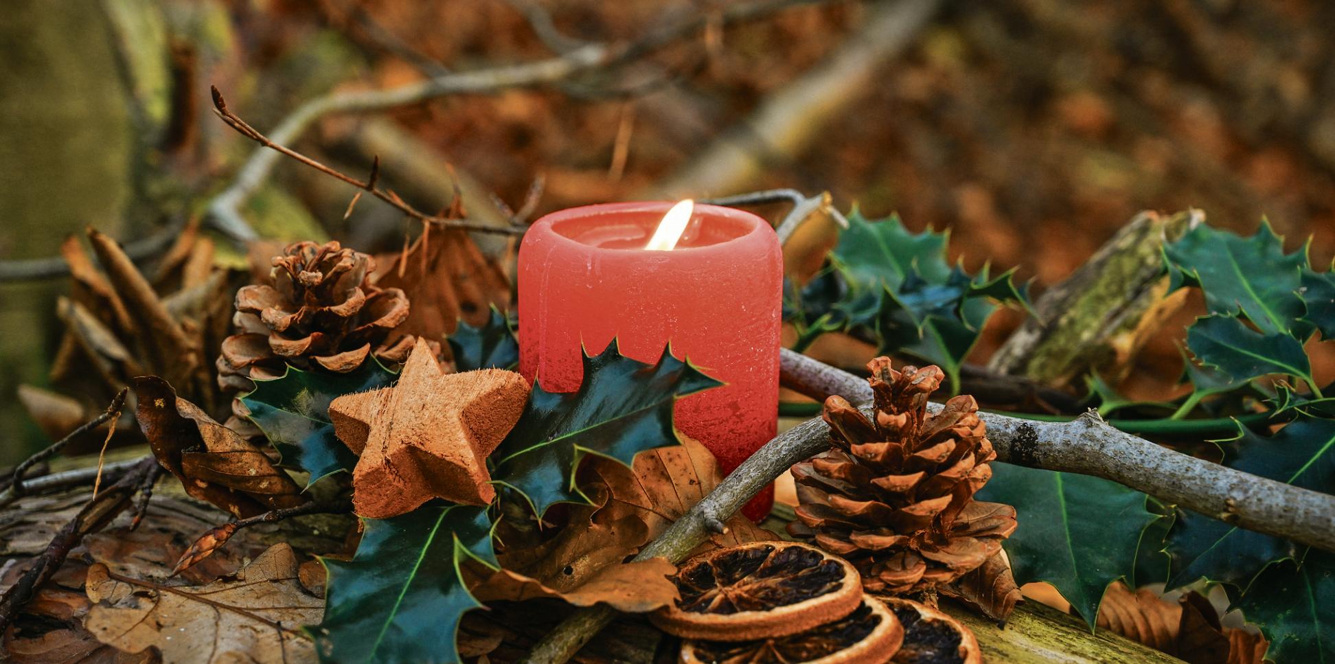Adventsgesteck mit brennender Kerze.