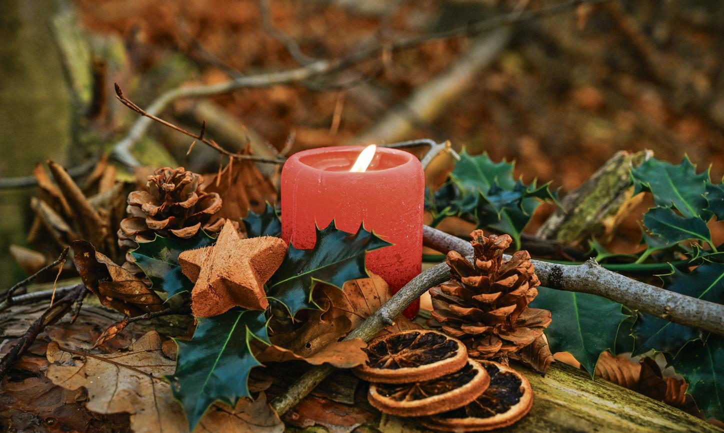 Adventsgesteck mit brennender Kerze.