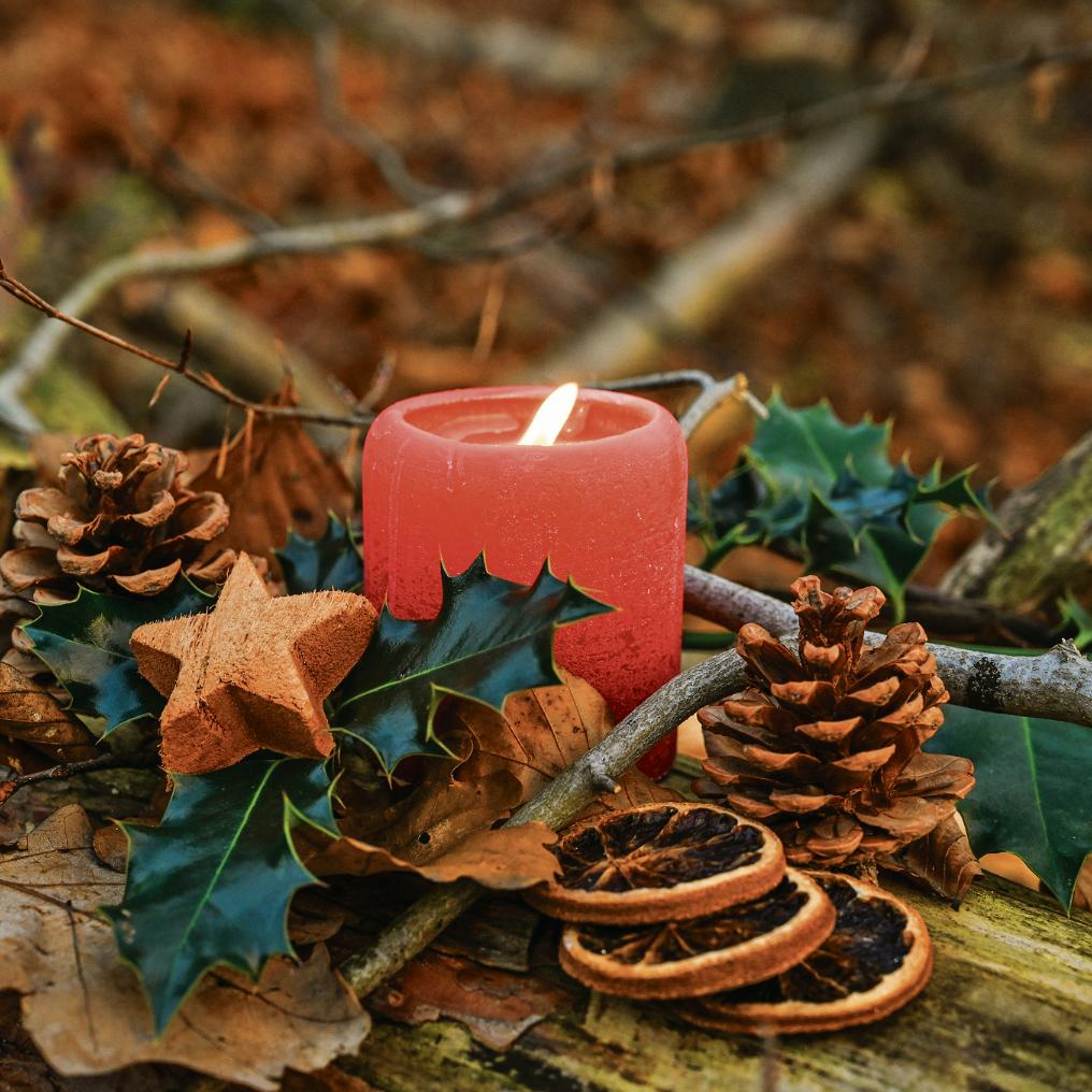 Adventsgesteck mit brennender Kerze.