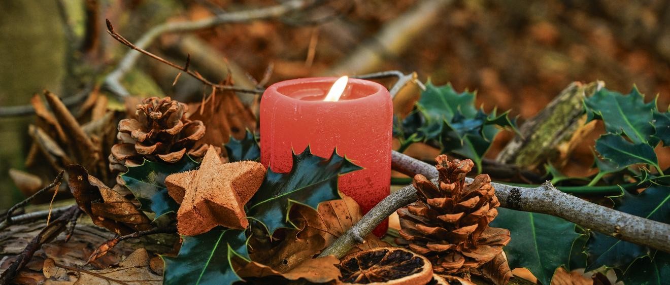 Adventsgesteck mit brennender Kerze.