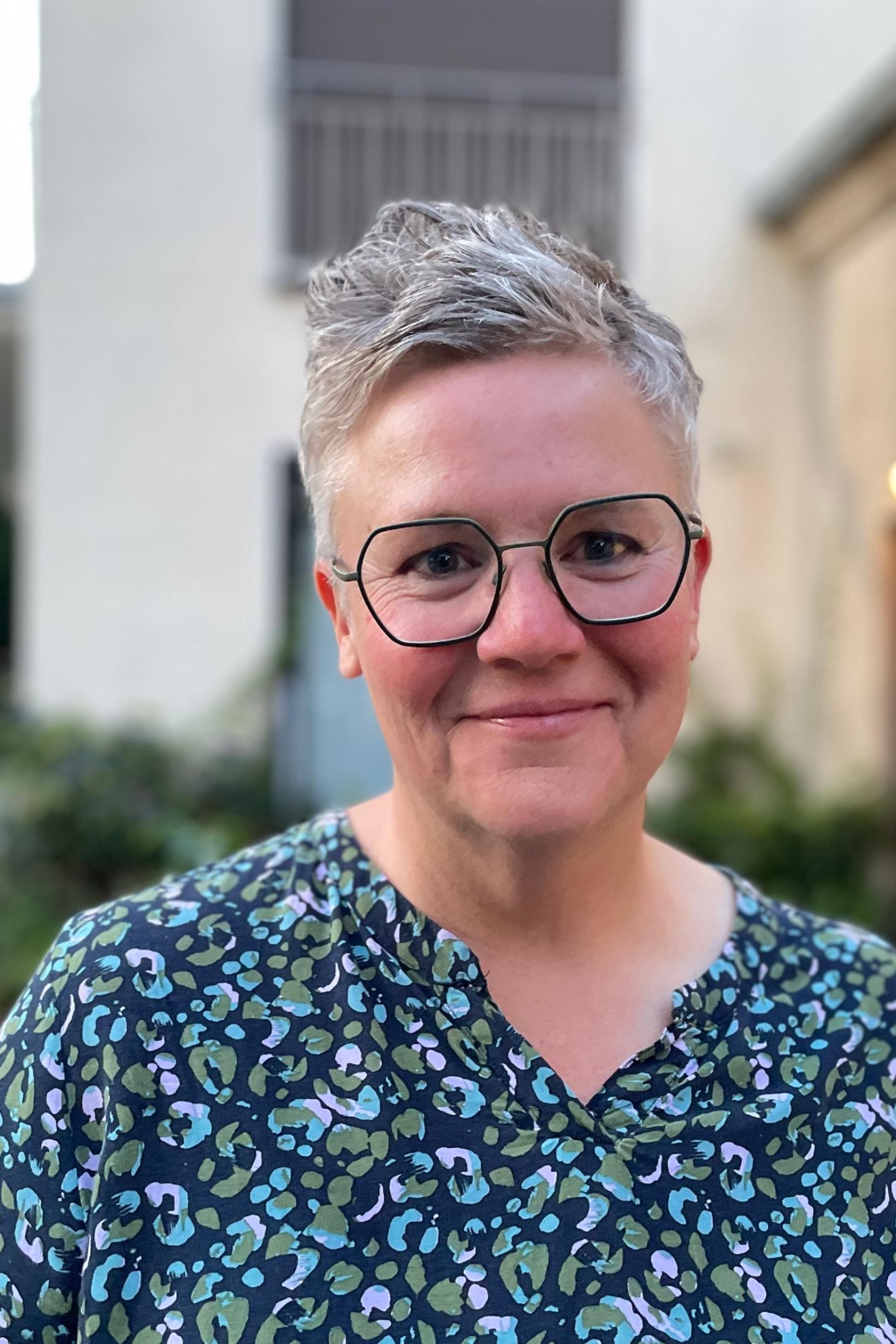 Eine Frau mit Brille und kurzen Haaren lächelt in die Kamera