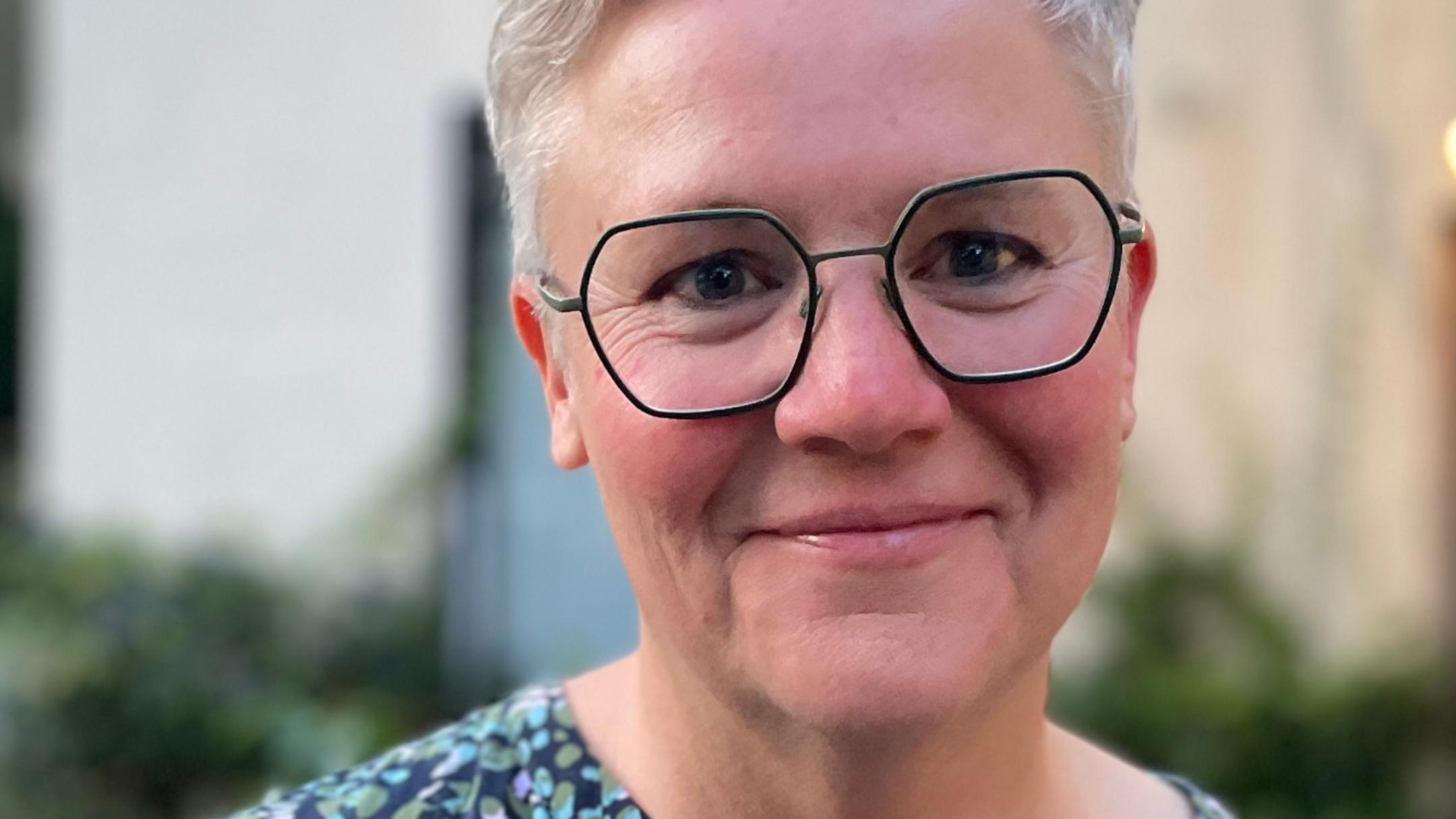 Eine Frau mit Brille und kurzen Haaren lächelt in die Kamera
