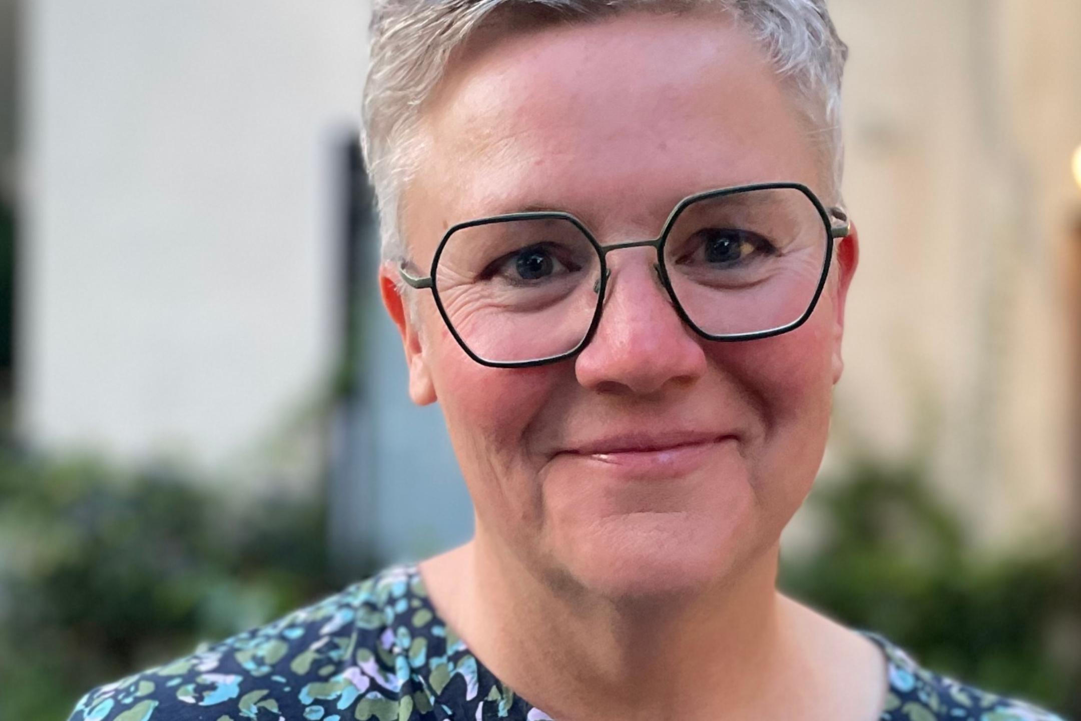 Eine Frau mit Brille und kurzen Haaren lächelt in die Kamera