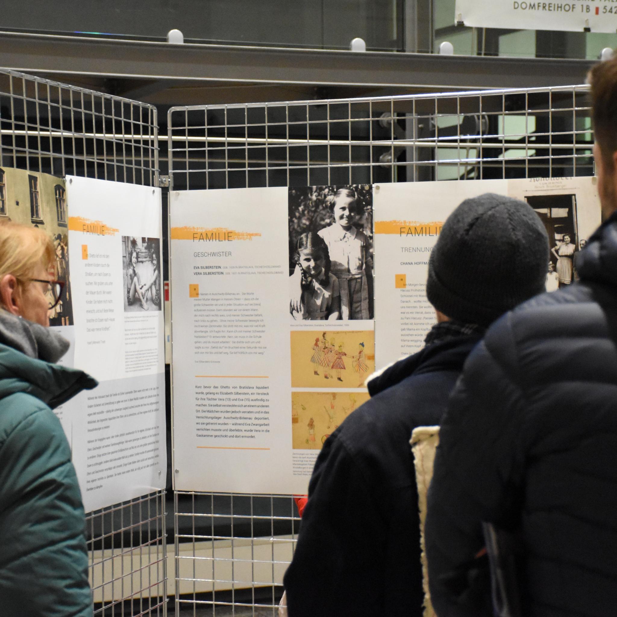 Besucher betrachten Infotafeln der Ausstellung.