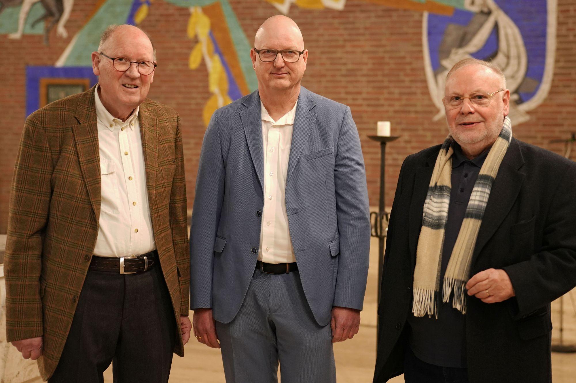 Drei Männer blicken lächelnd in die Kamera