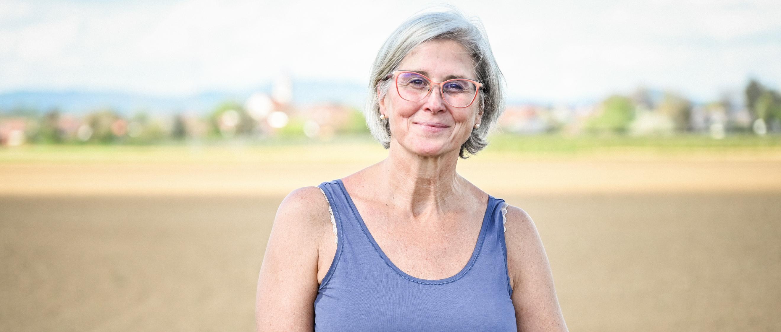 Eine lächelnde Frau steht vor einem Feld