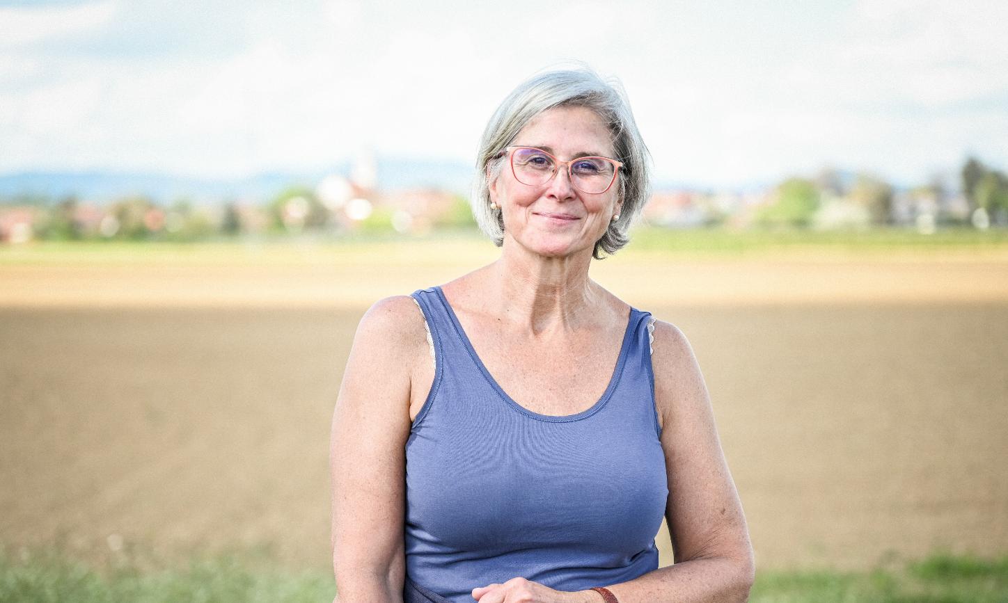 Eine lächelnde Frau steht vor einem Feld