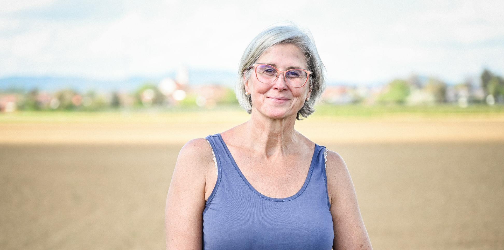 Eine lächelnde Frau steht vor einem Feld