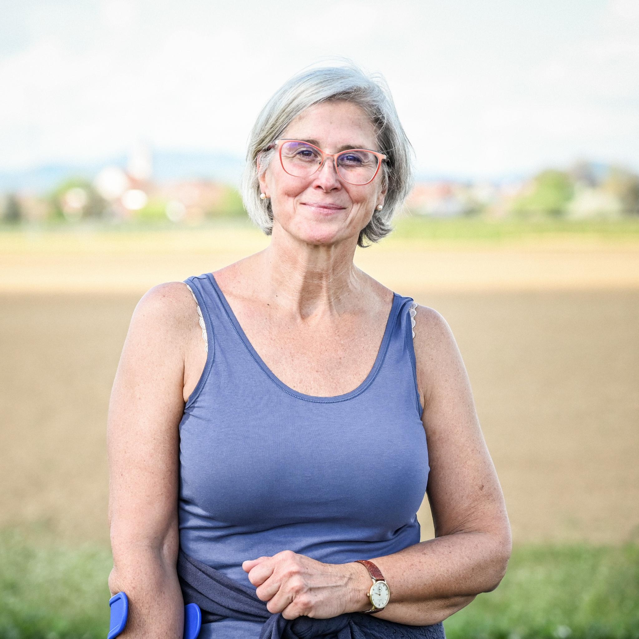 Eine lächelnde Frau steht vor einem Feld