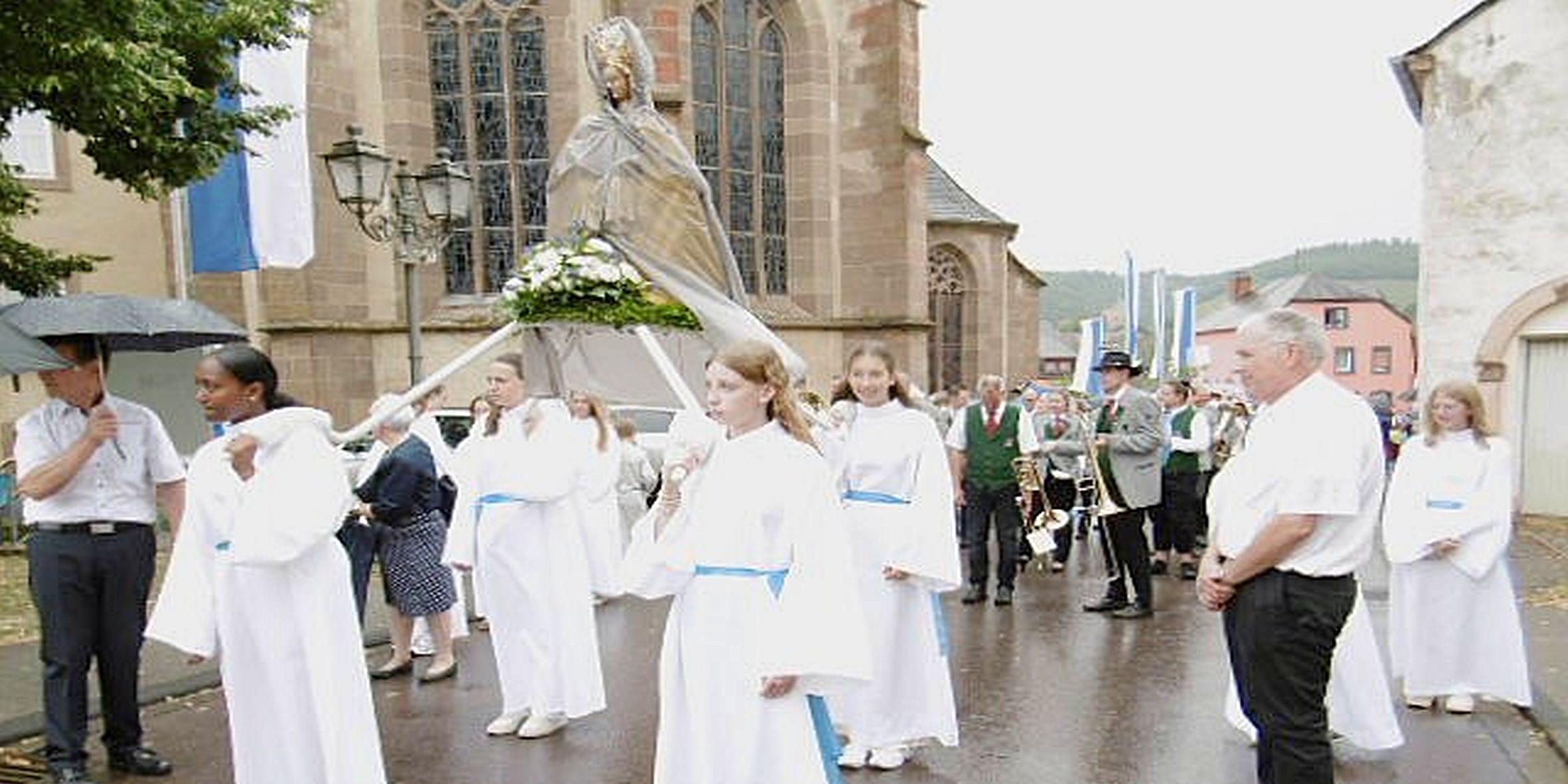 Weiß gekleidete Mädchen tragen eine Marienfigur
