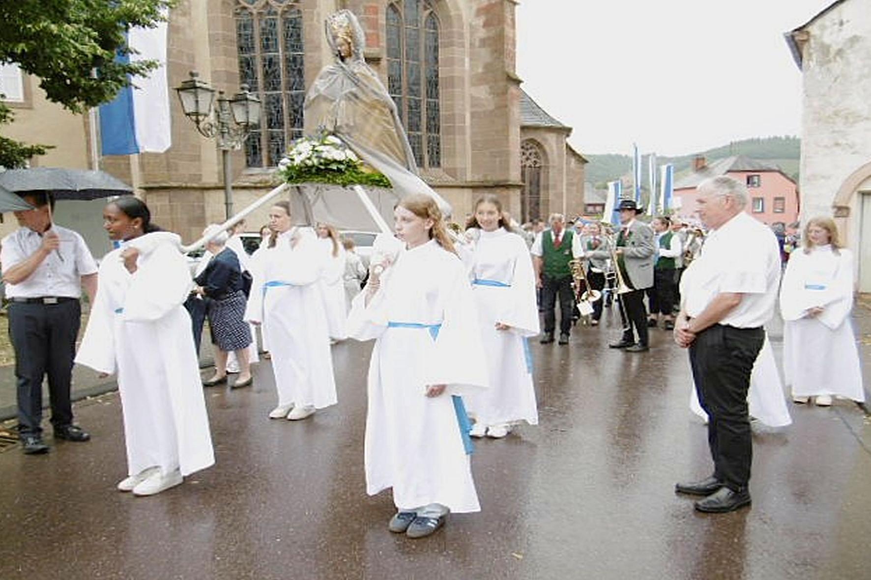 Weiß gekleidete Mädchen tragen eine Marienfigur