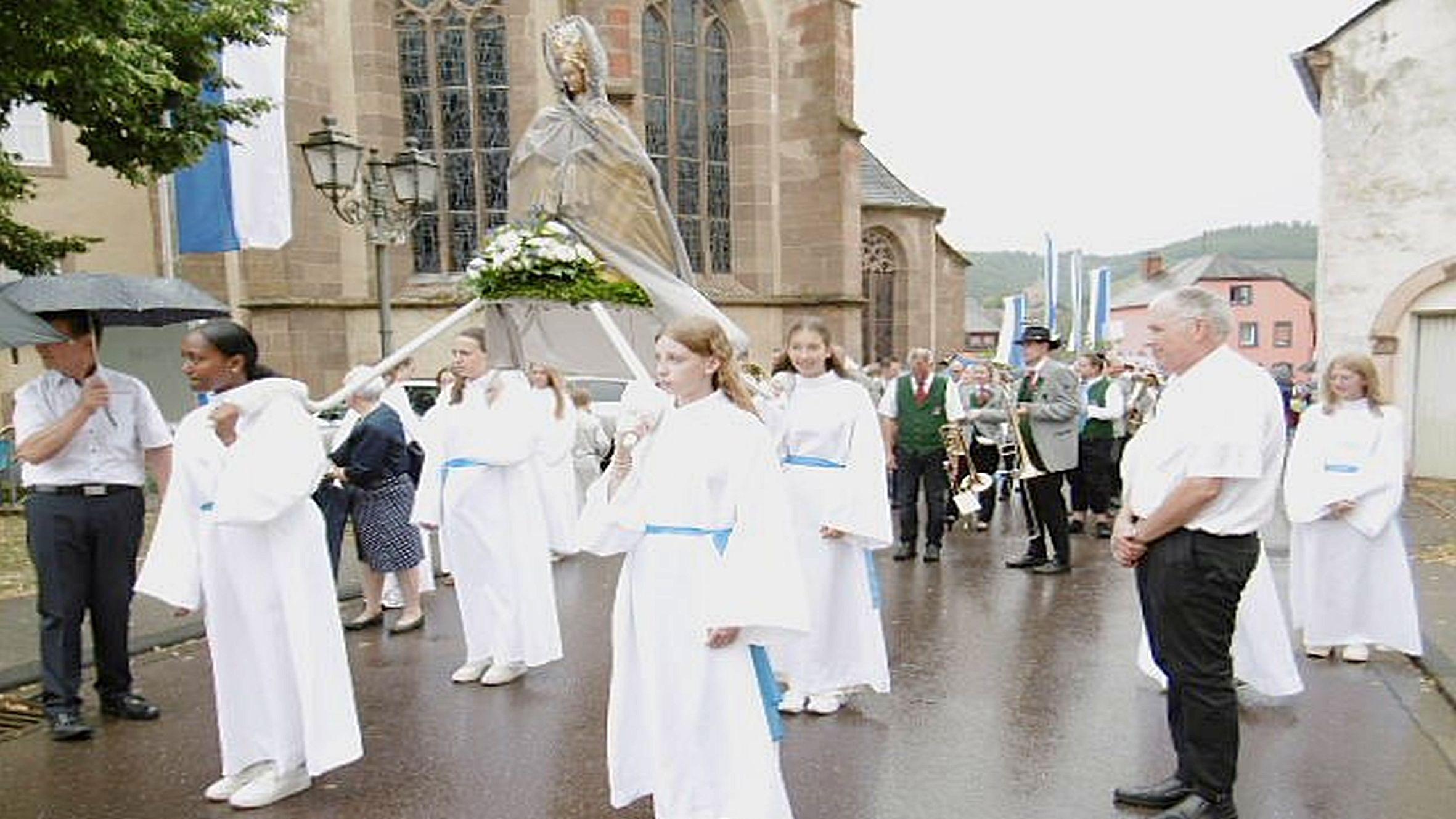 Weiß gekleidete Mädchen tragen eine Marienfigur