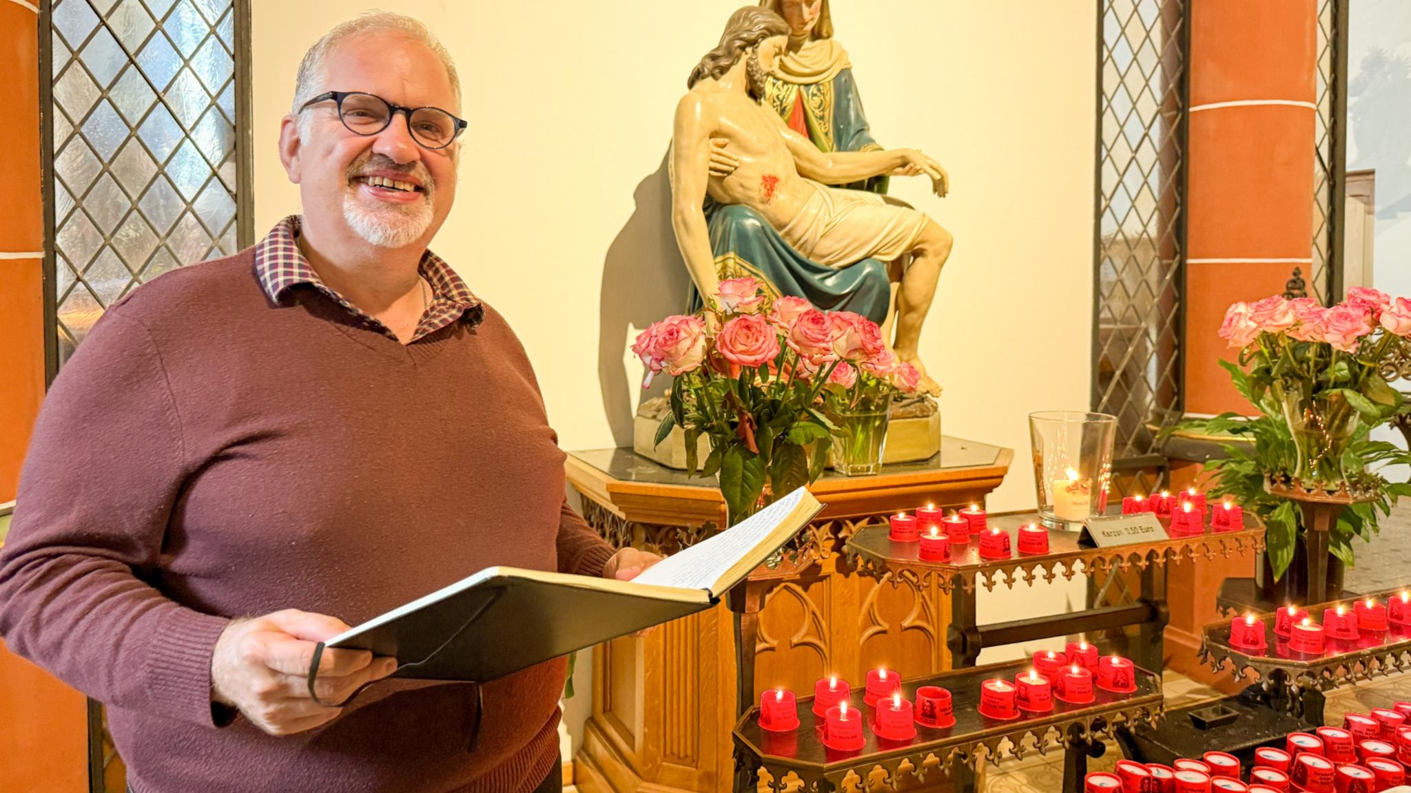 Bruder Jörg mit einem Buch vor der Pietà in der Klosterkirche des Trierer Brüderkrankenhauses.