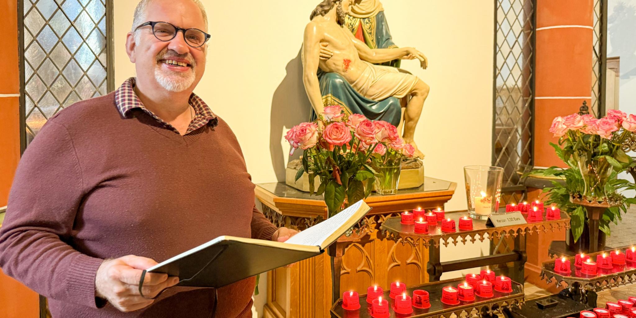 Bruder Jörg mit einem Buch vor der Pietà in der Klosterkirche des Trierer Brüderkrankenhauses.