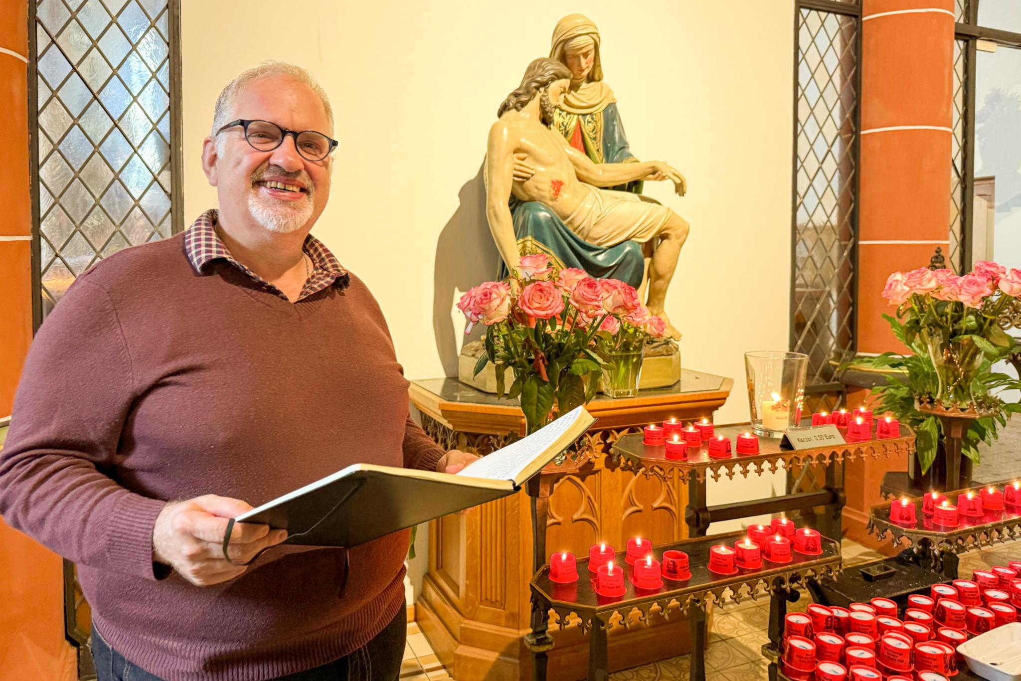 Bruder Jörg mit einem Buch vor der Pietà in der Klosterkirche des Trierer Brüderkrankenhauses.