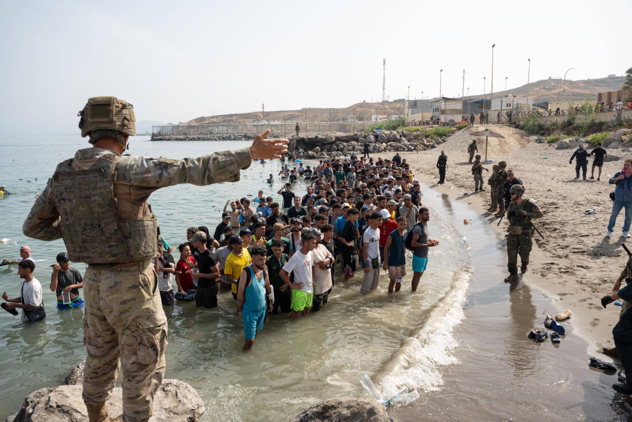 Menschen stehen mit Kleidern im Wasser, im Vordergrund ein Soldat