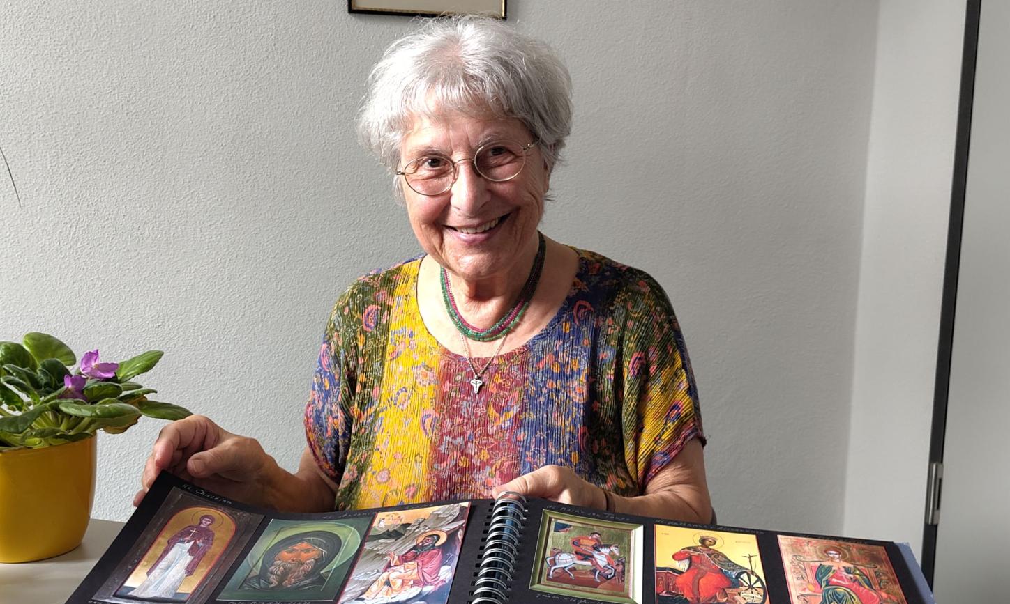Eine grauhaarige Frau zeigt Bilder in einem Album