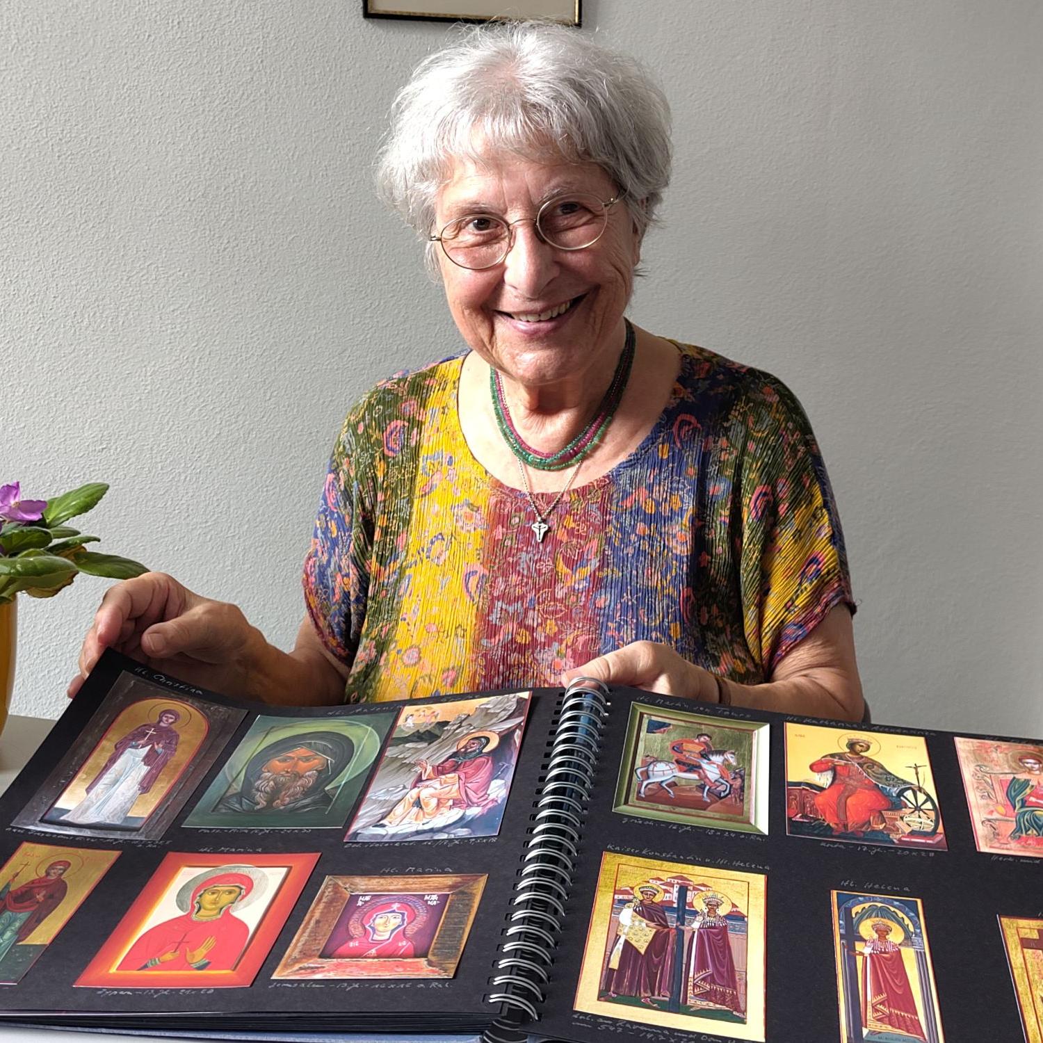 Eine grauhaarige Frau zeigt Bilder in einem Album