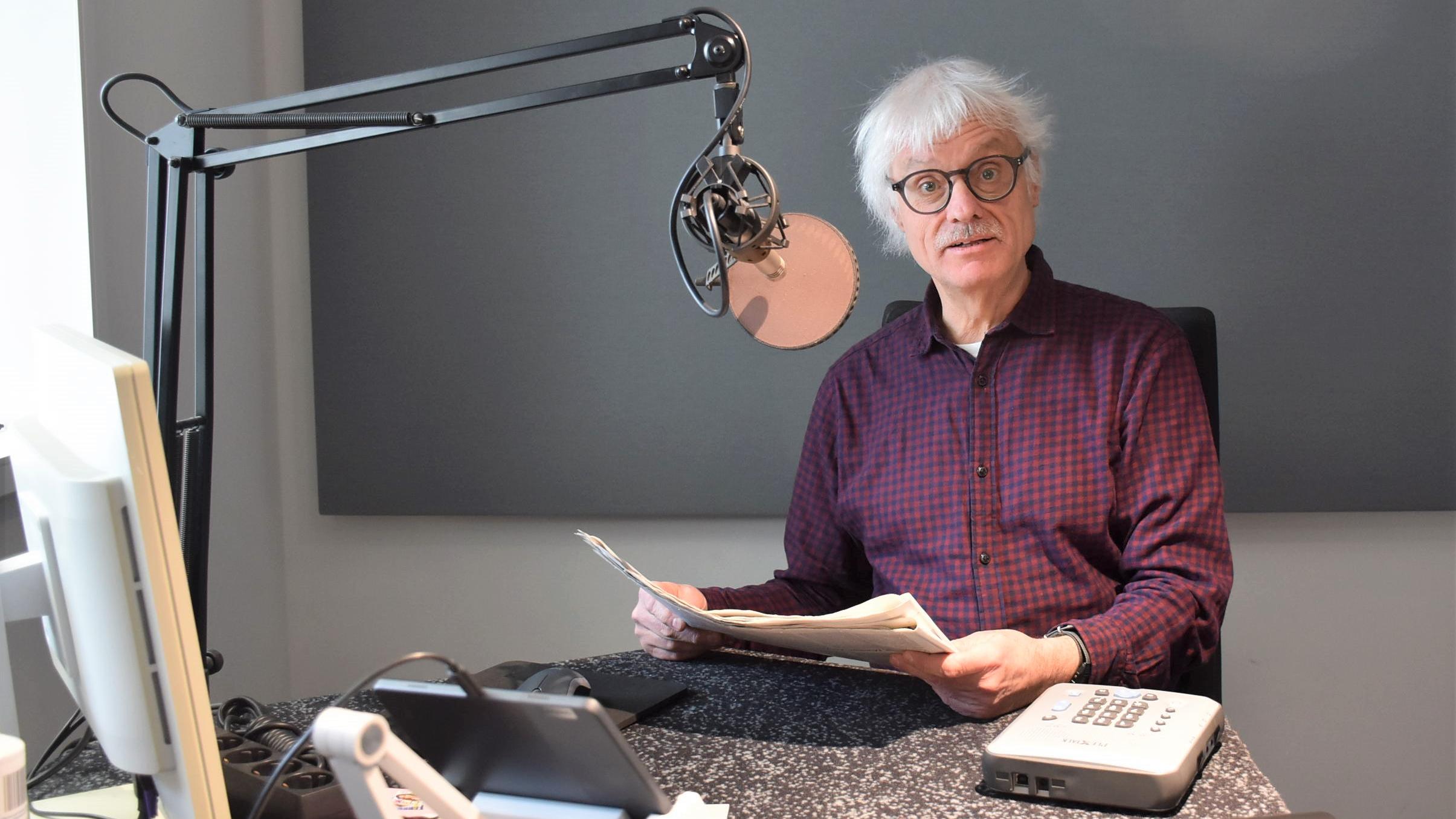 Ein Mann mit Papier in den Händen sitzt vor einem Mikrofon