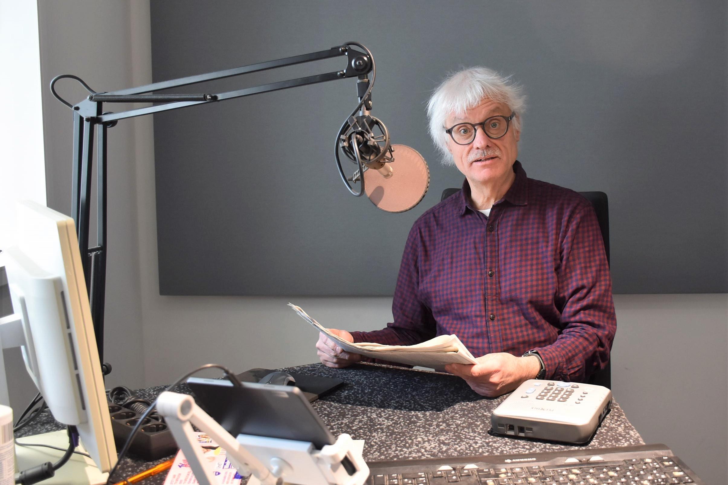 Ein Mann mit Papier in den Händen sitzt vor einem Mikrofon