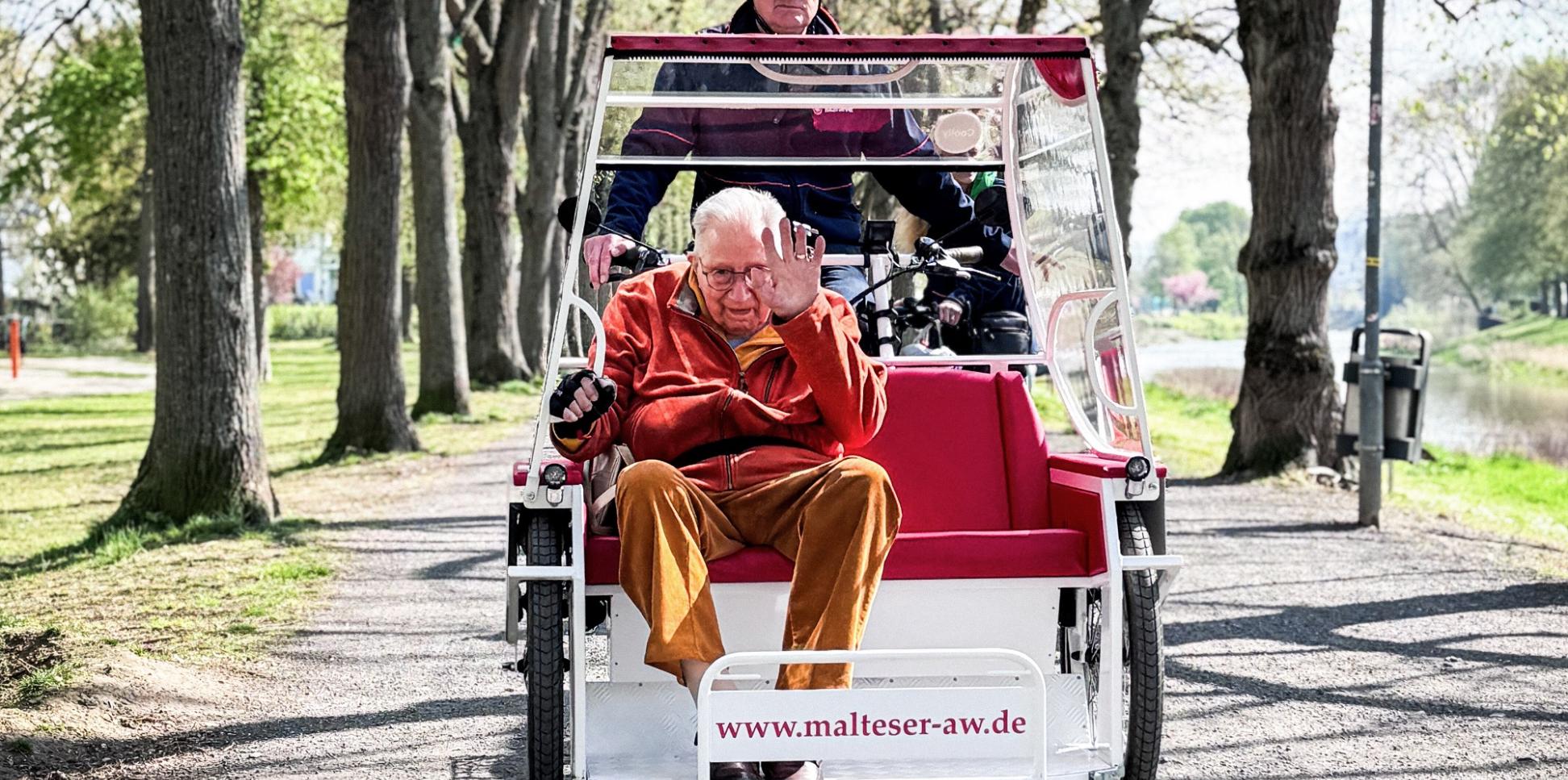 Kurt Braunisch, ehrenamtlicher Mitarbeiter beim Malteser Hilfsdienst, fährt Senior Franz Lieder an der Ahr entlang mit der E-Rikscha in Bad Neuenahr-Ahrweiler.