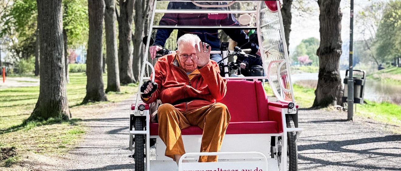 Kurt Braunisch, ehrenamtlicher Mitarbeiter beim Malteser Hilfsdienst, fährt Senior Franz Lieder an der Ahr entlang mit der E-Rikscha in Bad Neuenahr-Ahrweiler.