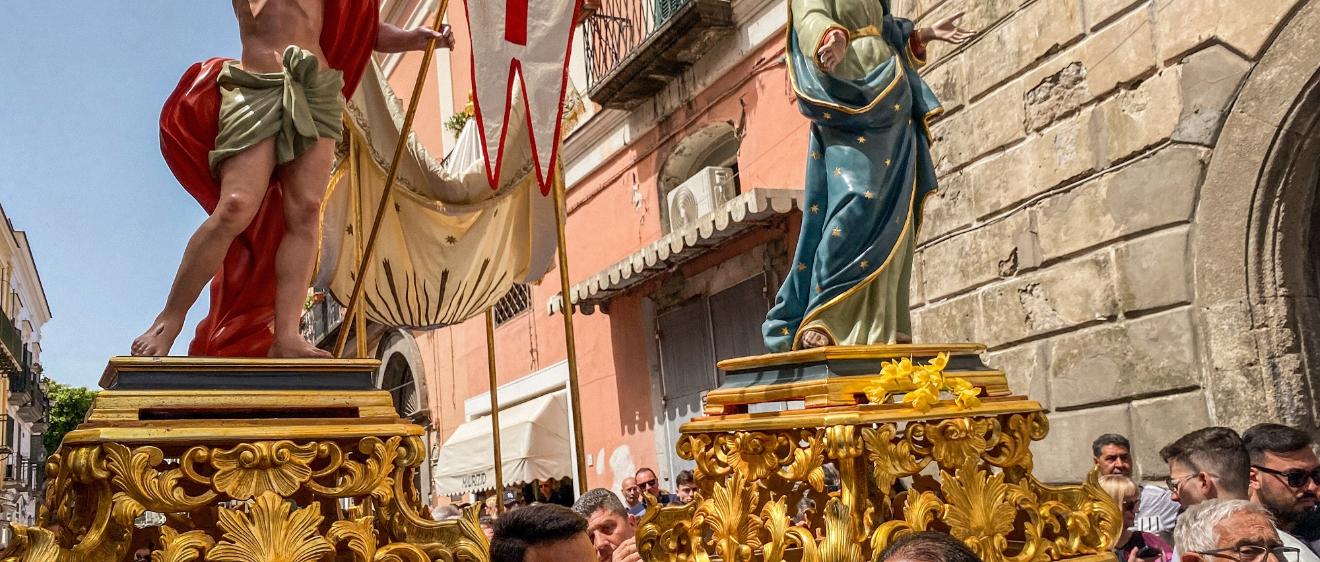 Kostümierte Männer, Mitglieder der Erzbruderschaft Santa Maria Visitapoveri, tragen Statuen von Jesus und Maria bei einer Prozession an Ostersonntag 2025 auf der Insel Ischia in Italien.