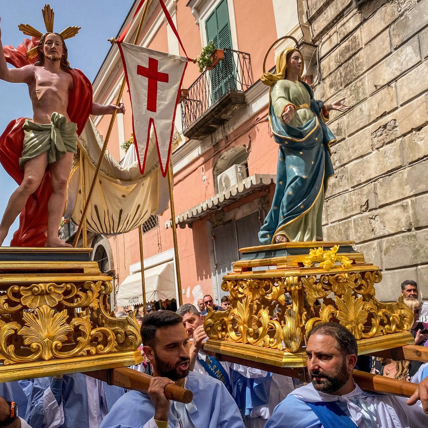 Kostümierte Männer, Mitglieder der Erzbruderschaft Santa Maria Visitapoveri, tragen Statuen von Jesus und Maria bei einer Prozession an Ostersonntag 2025 auf der Insel Ischia in Italien.
