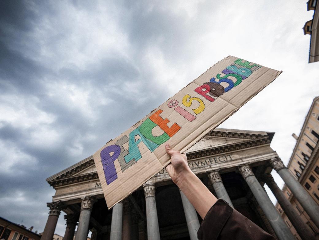 Ein Stück Pappe mit der Aufschrift „Peace is possible“ – „Frieden ist möglich“ wird hochgehalten.
