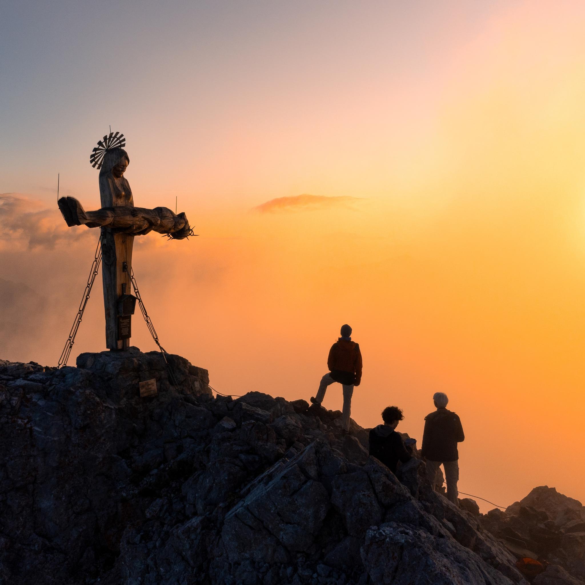 Das Gipfelkreuz in Form einer stehenden Pietà auf der Schönfeldspitze in Österreich bei Sonnenaufgang.