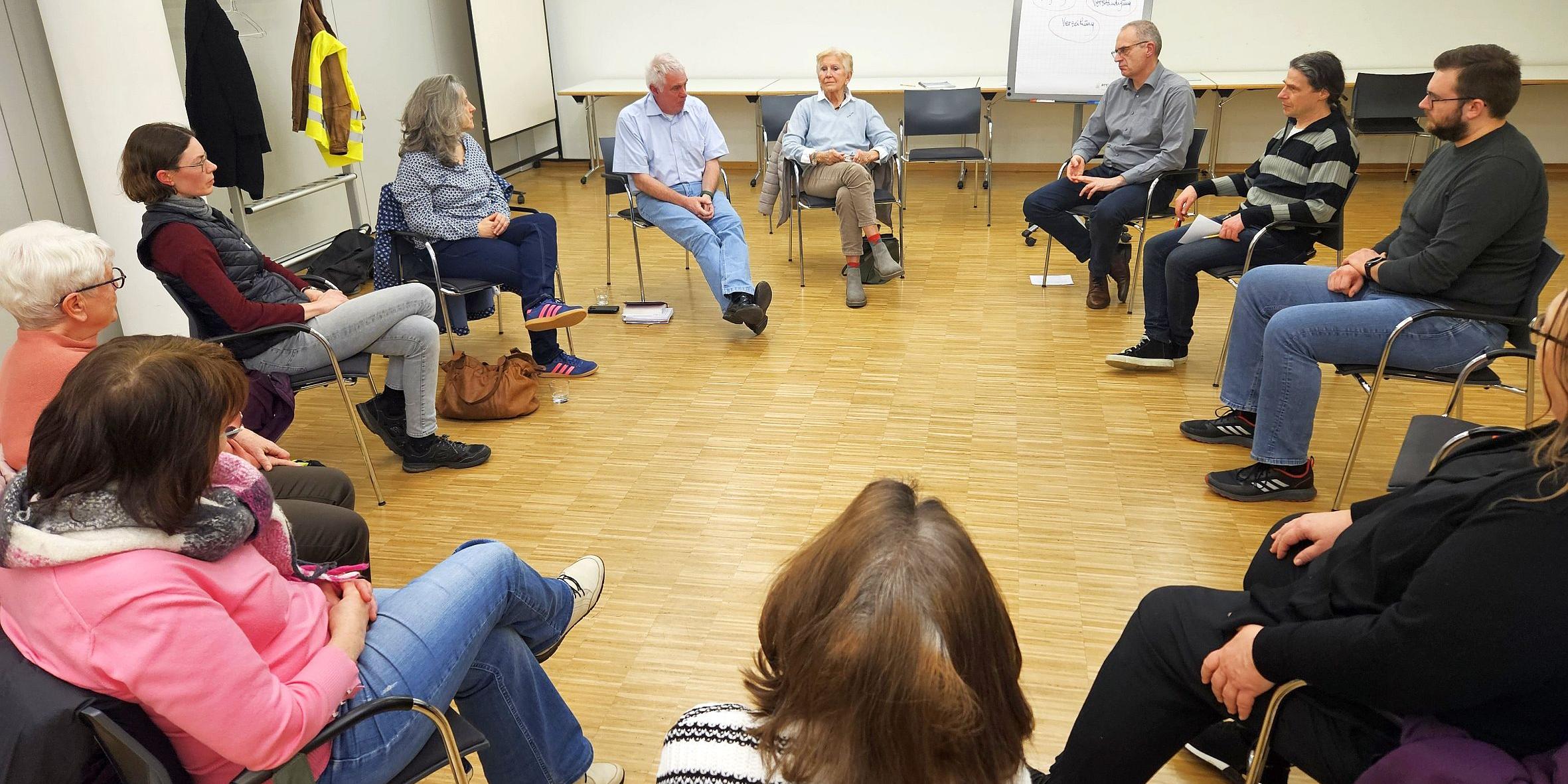 Mehrere Menschen sitzen im Kreis und tauschen sich aus