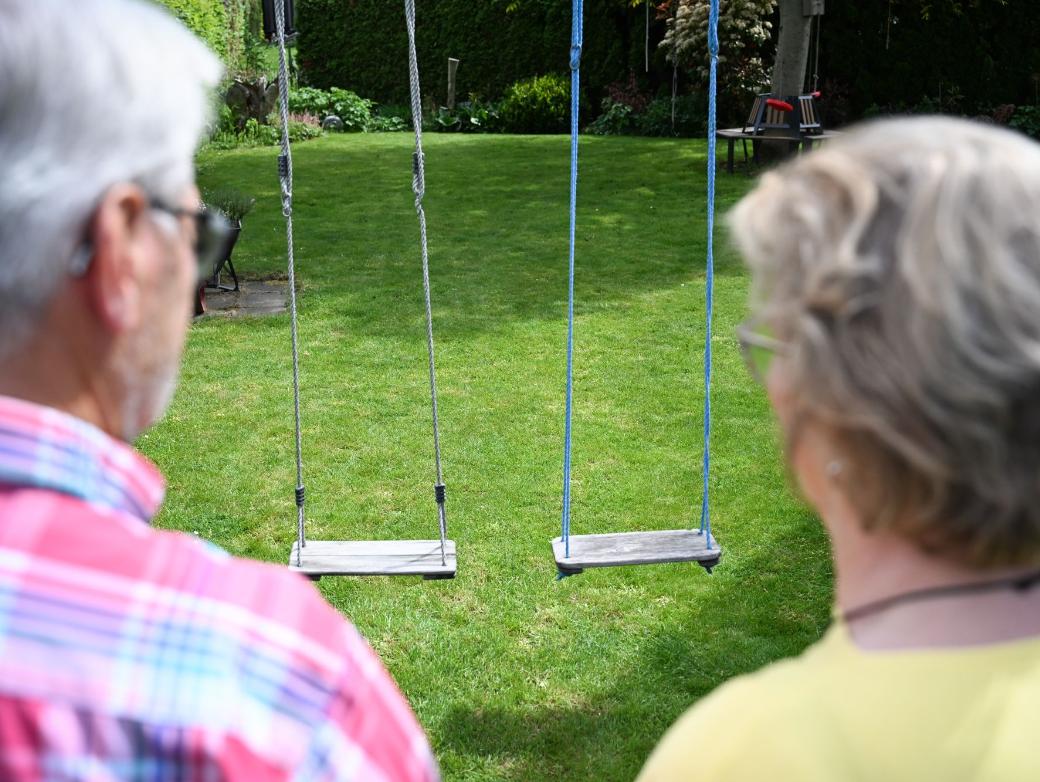 Zwei Personen von hinten gezeigt schauen auf eine leere Schaukel