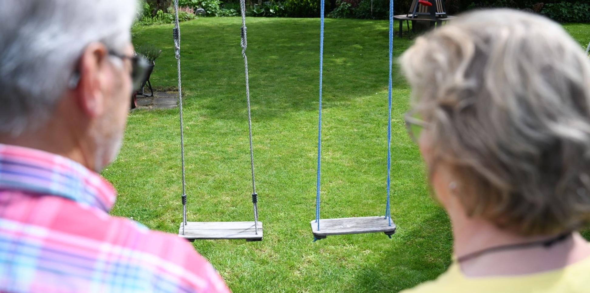 Zwei Personen von hinten gezeigt schauen auf eine leere Schaukel