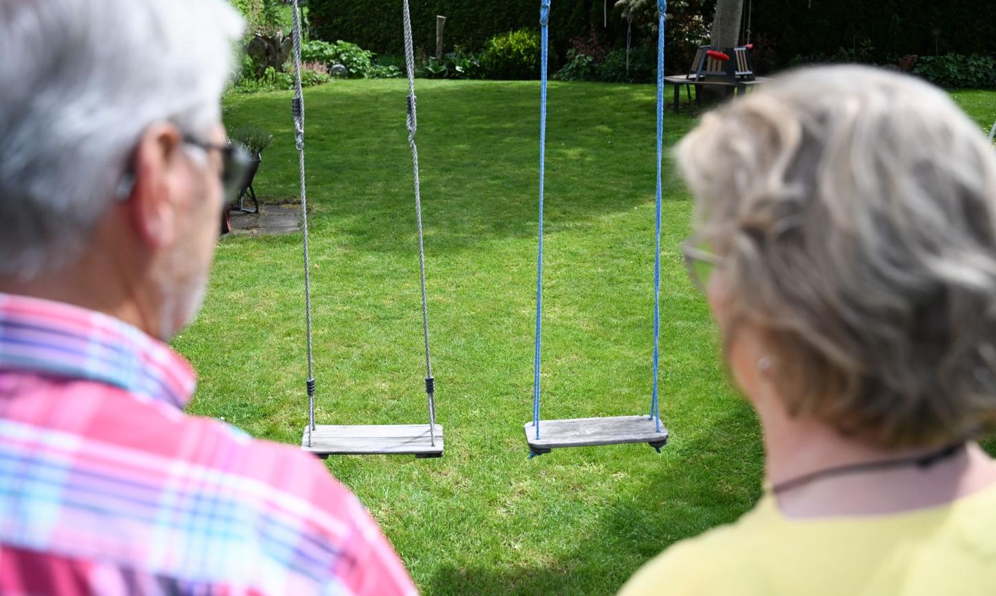 Zwei Personen von hinten gezeigt schauen auf eine leere Schaukel