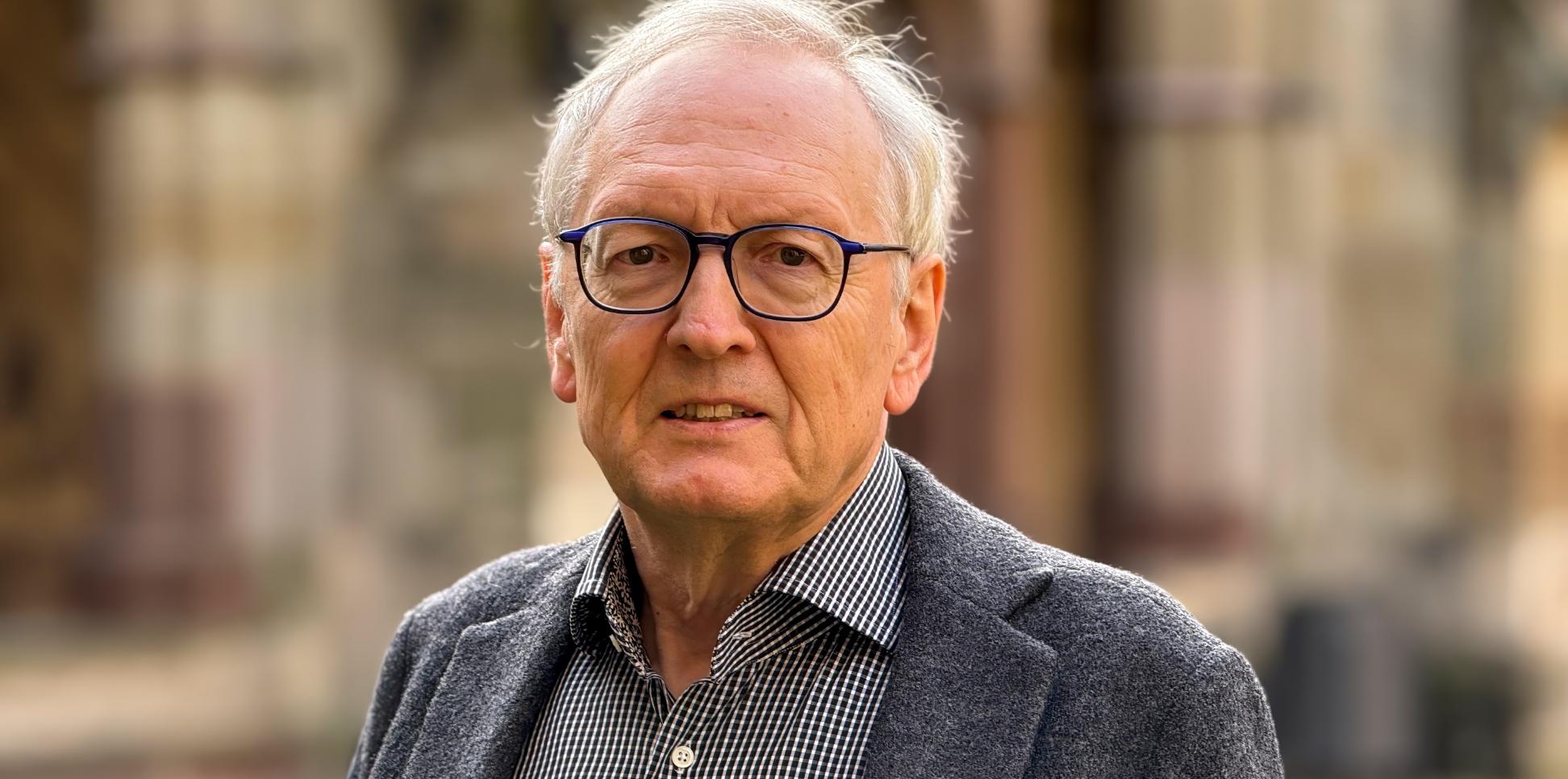 Ein älterer Herr mit Brille blickt in die Kamera