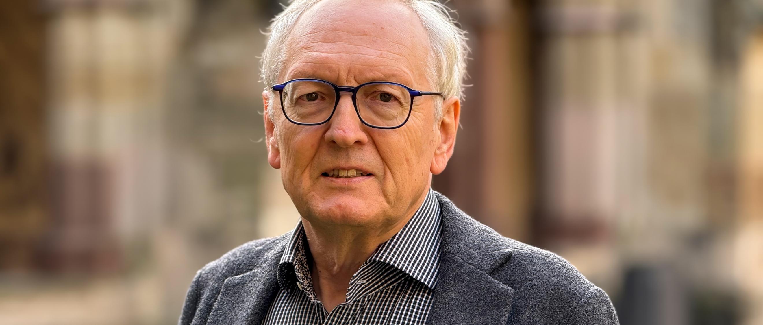 Ein älterer Herr mit Brille blickt in die Kamera