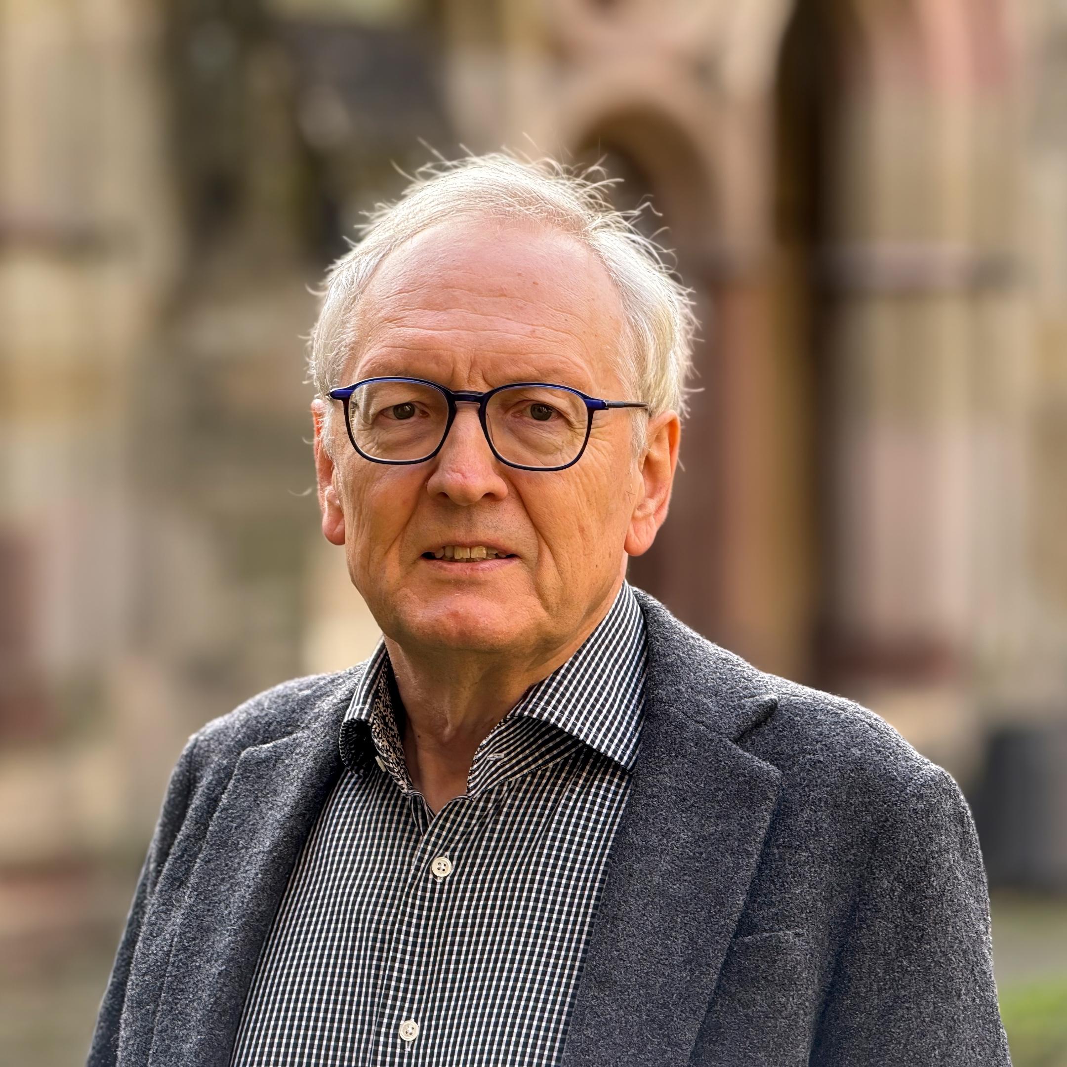 Ein älterer Herr mit Brille blickt in die Kamera