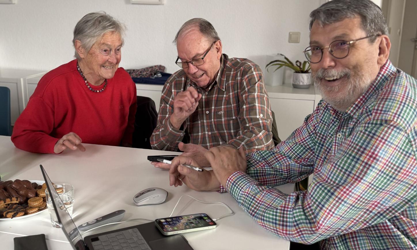 Zwei Teilnehmer gemeinsam mit Ingo Neumann (rechts) mit digitalen Geräten an einem Tisch.
