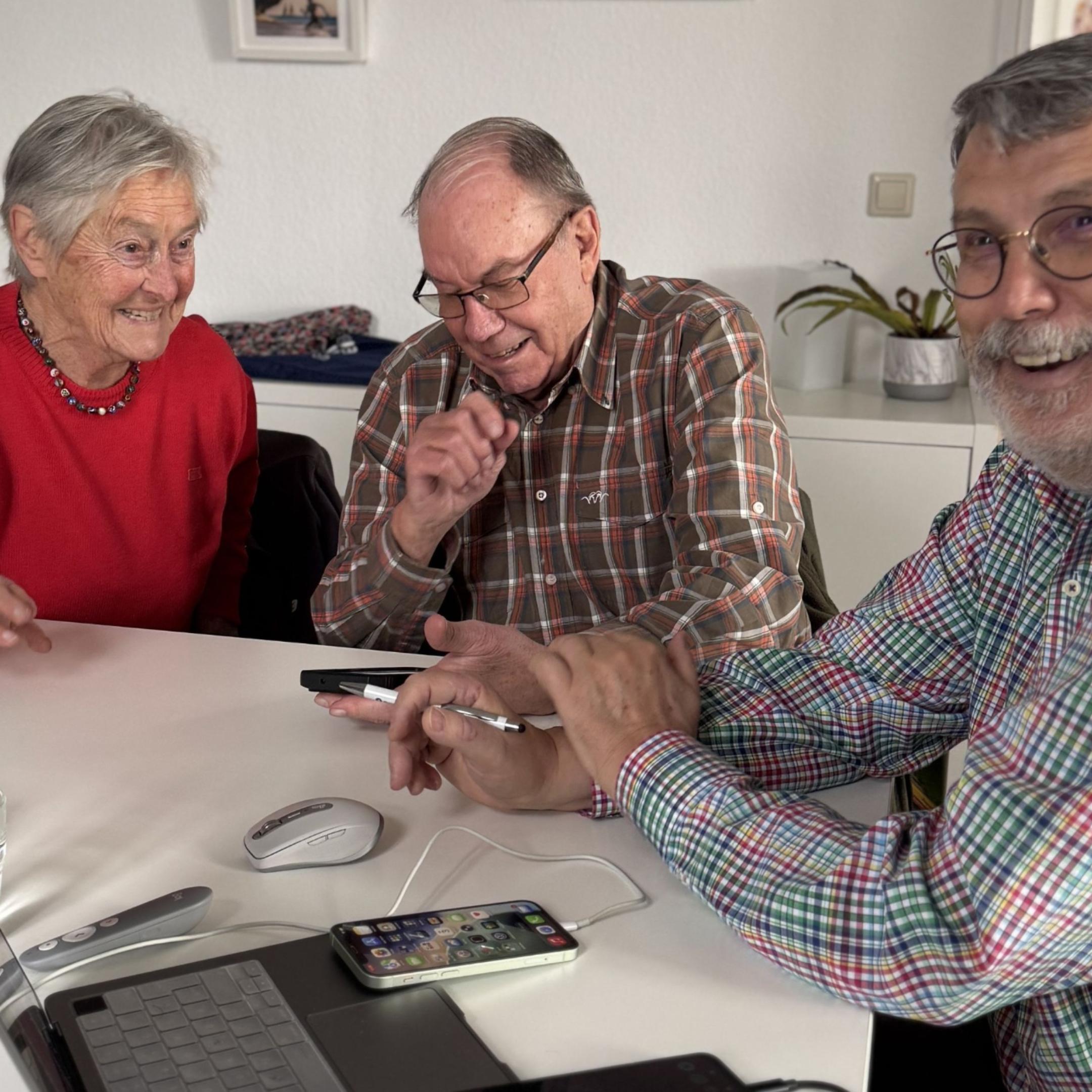 Zwei Teilnehmer gemeinsam mit Ingo Neumann (rechts) mit digitalen Geräten an einem Tisch.
