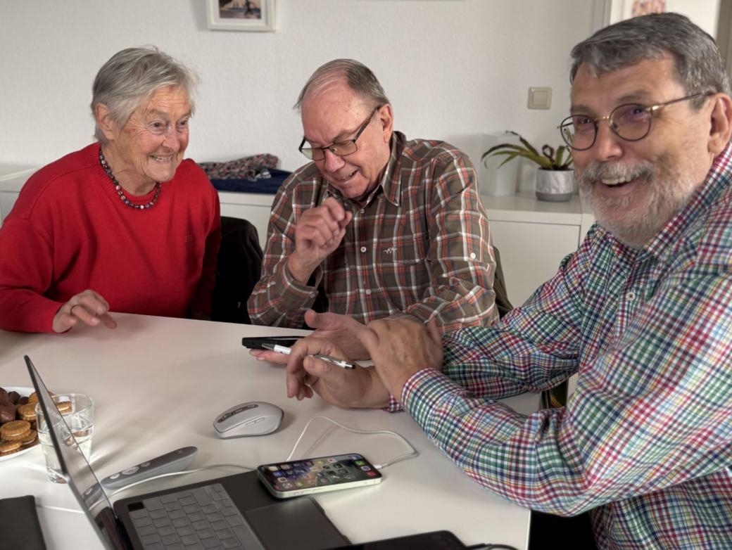 Zwei Teilnehmer gemeinsam mit Ingo Neumann (rechts) mit digitalen Geräten an einem Tisch.