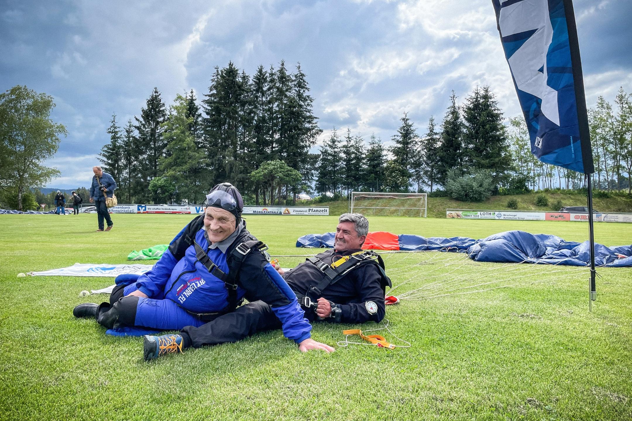 Pfarrer Huber (63, links) und ein Mitglied seines Teams nach der Fallschirmlandung am 22. Juni auf einer Wiese in Schwabbruck