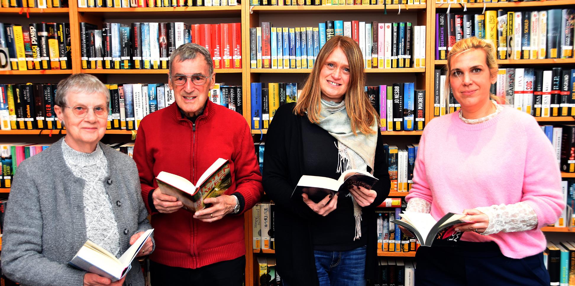 Ein Mann und drei Frauen mit Büchern in den Händen vor einem Bücherregal