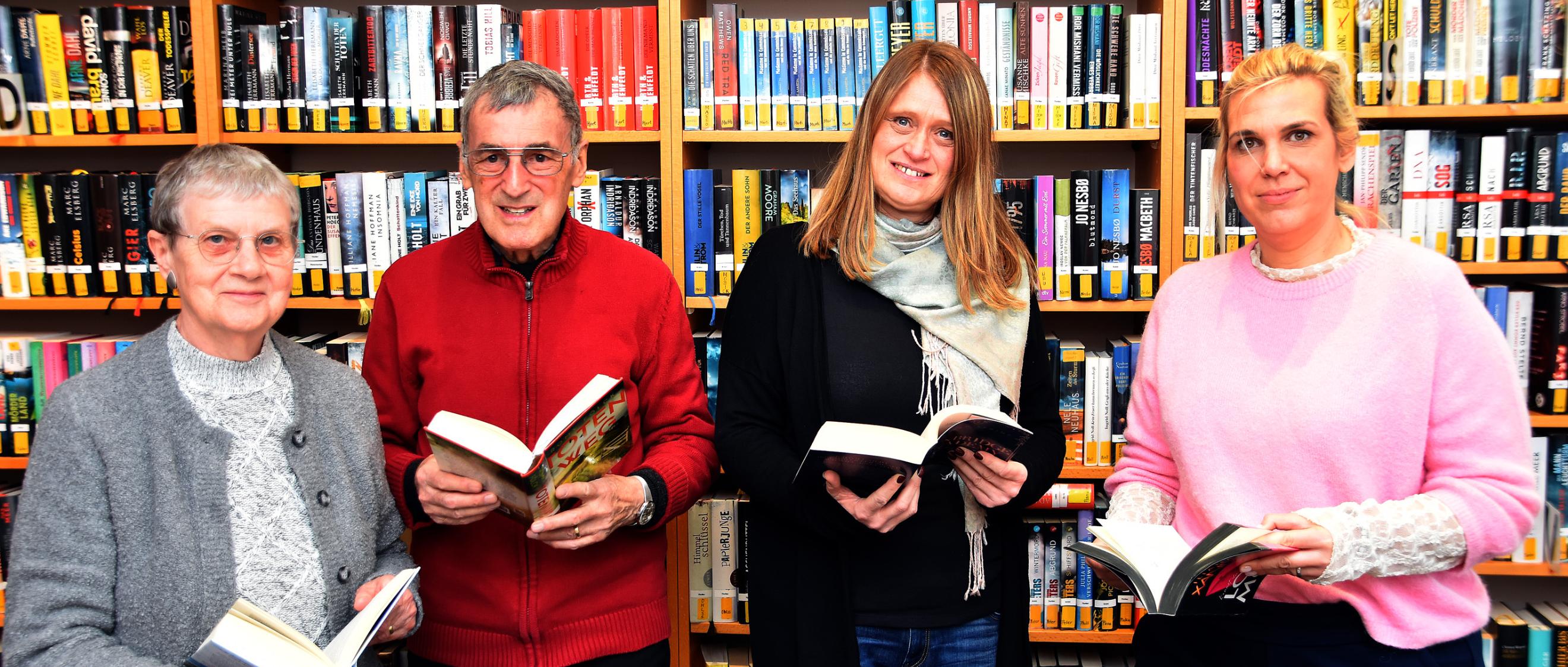 Ein Mann und drei Frauen mit Büchern in den Händen vor einem Bücherregal