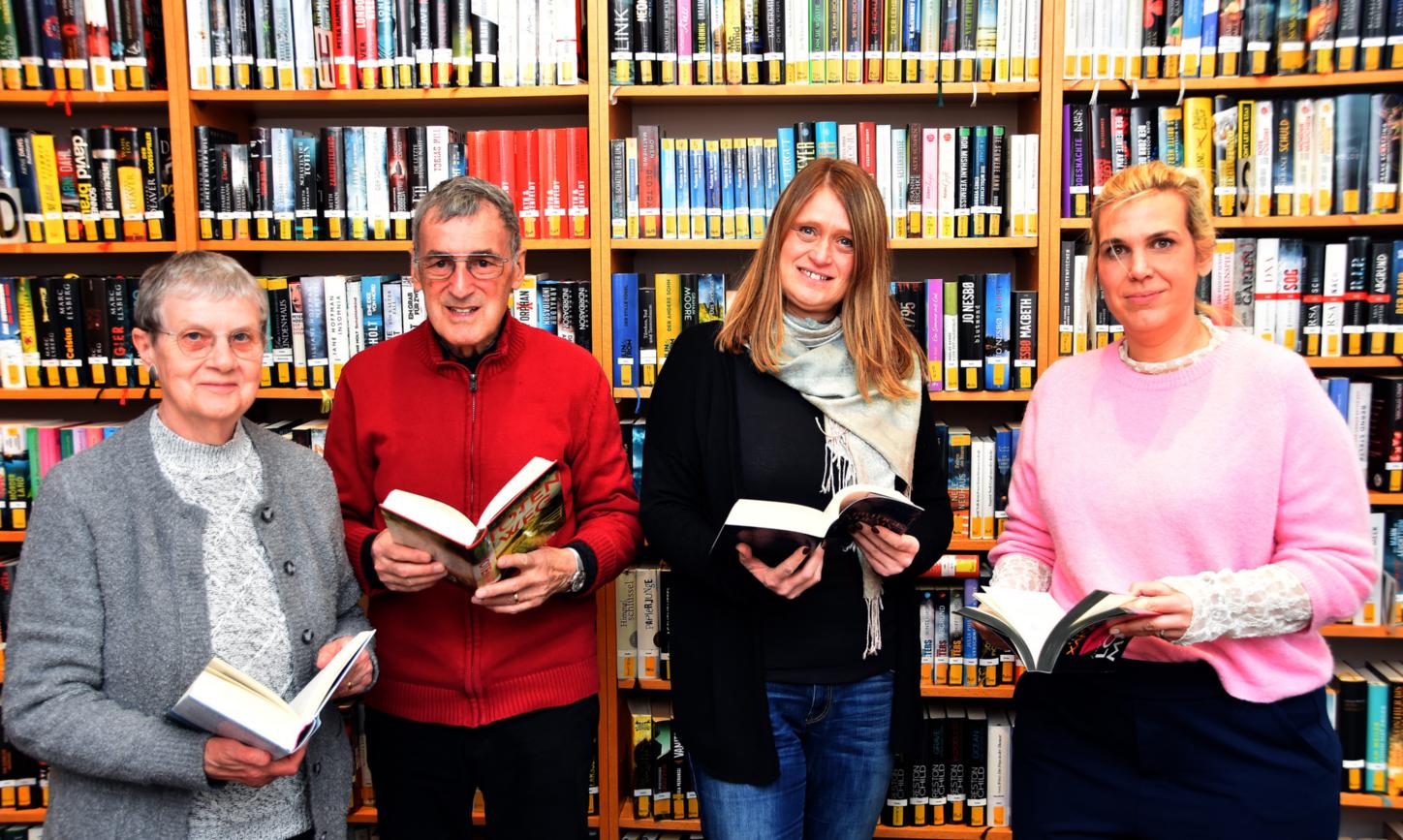 Ein Mann und drei Frauen mit Büchern in den Händen vor einem Bücherregal