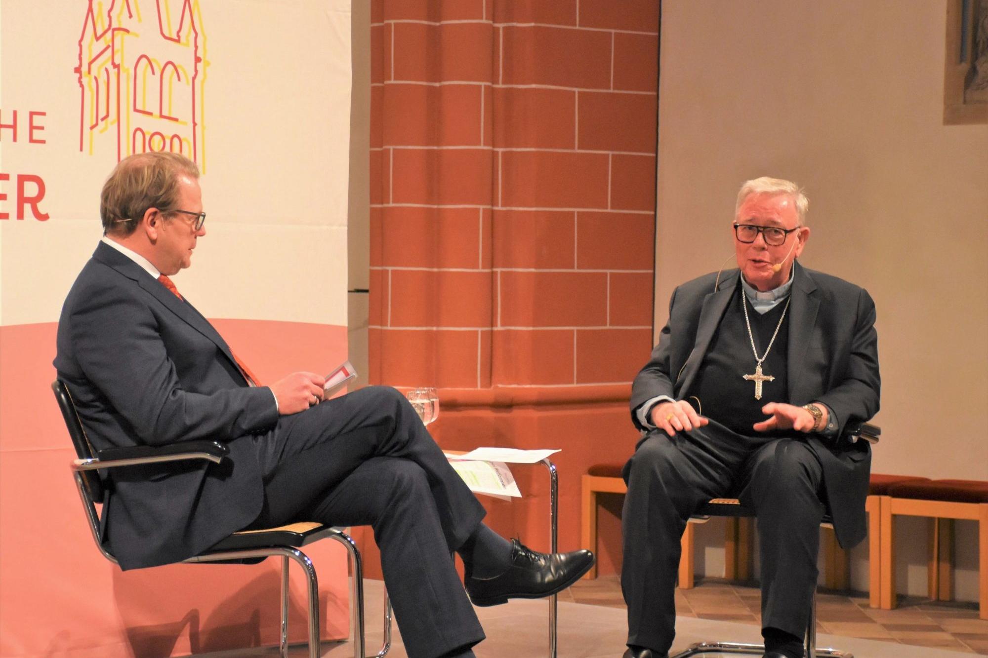 Zwei Männer sitzen auf einer Bühne und unterhalten sich